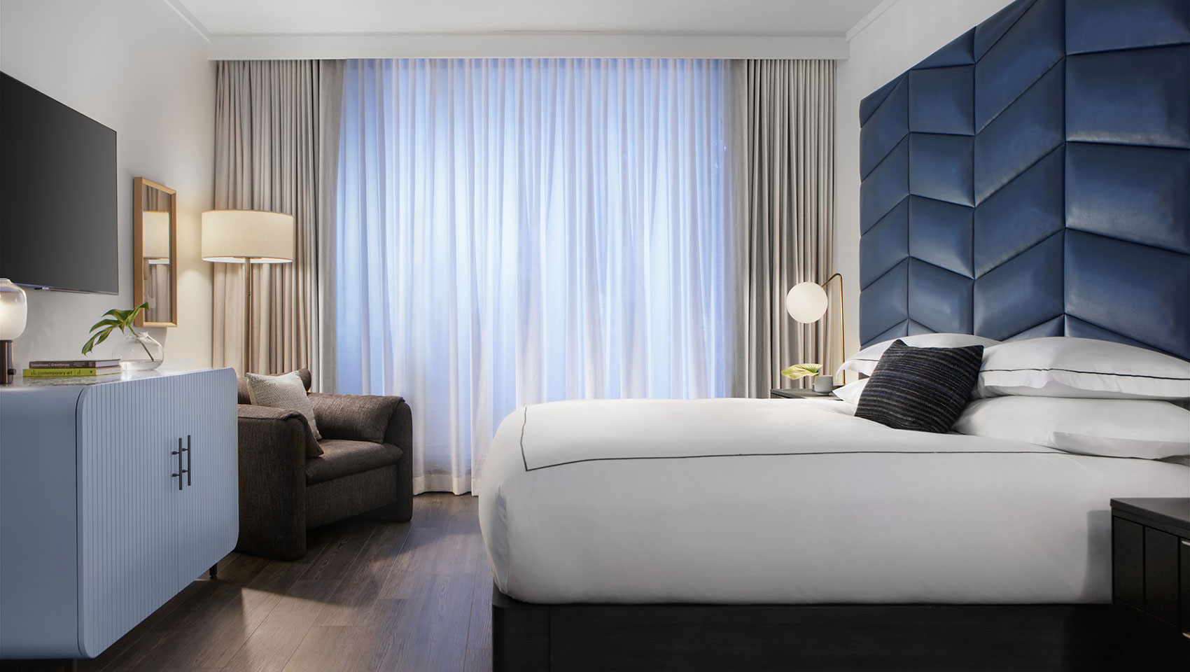 Kimpton Shane guestroom with large white king size bed and blue headboard