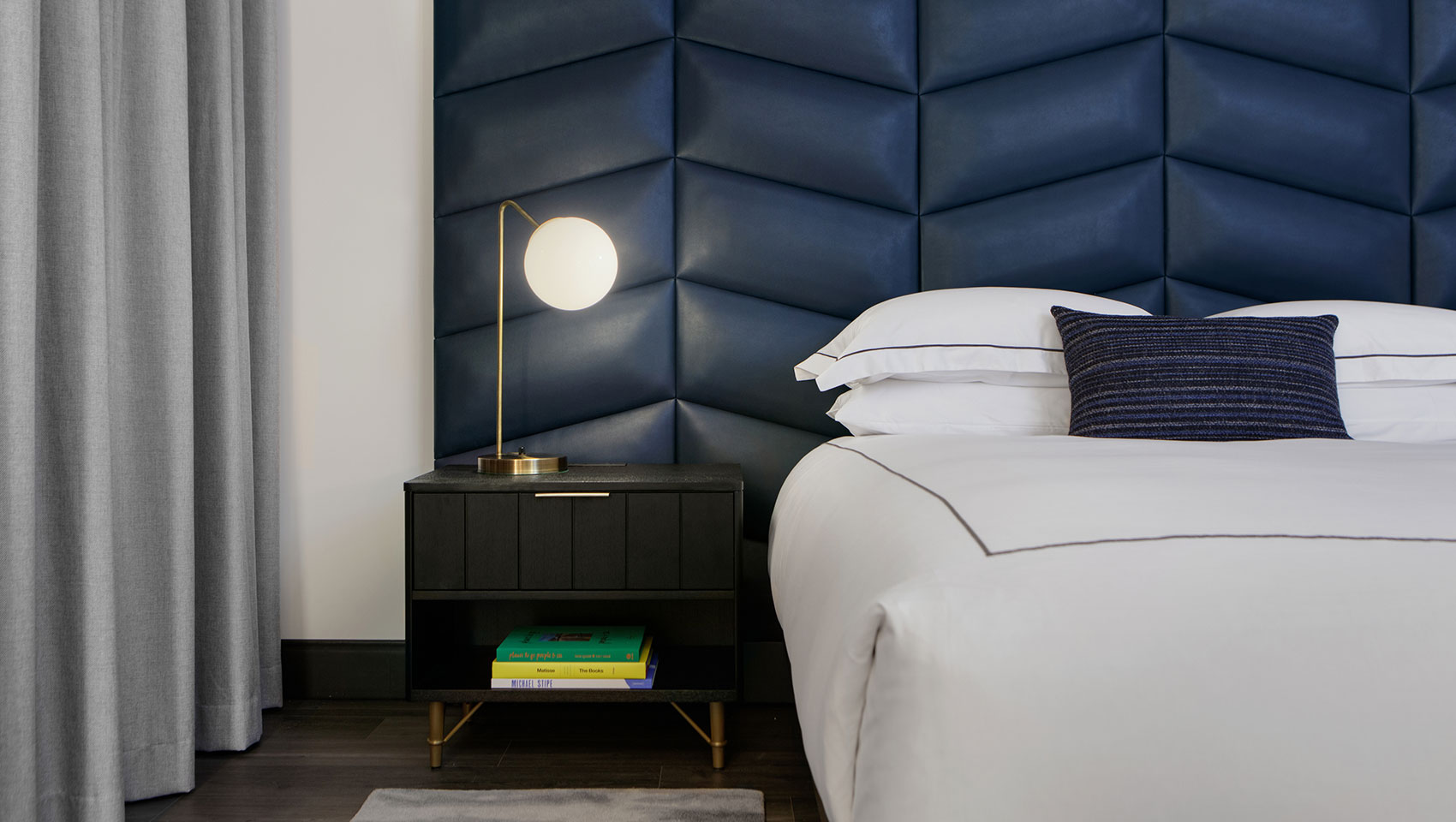 Kimpton Shane guestroom with large white king size bed, nightstand and blue headboard