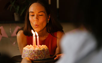 Woamn blowing out candles on a cake